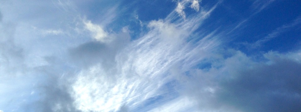 Wide view of a blue sky with wispy white and gray clouds; calm, airy mood.
